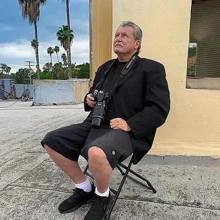 Robert Bingham seated outdoors with a camera, looking skyward